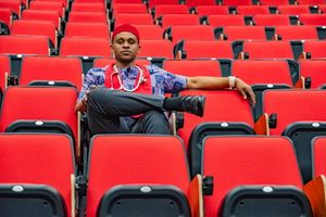Empty red stadium seats in rows with scattered spectators creating a minimalist pattern.