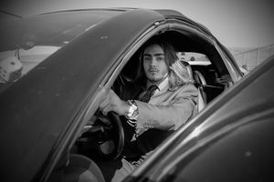 A black and white photo sequence showing a race car driver entering and sitting in the cockpit of a vehicle.