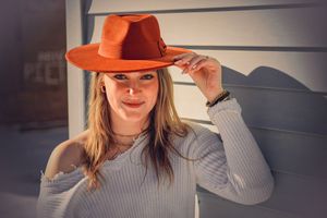 A person wearing an orange fedora hat and gray sweater poses in a series of stylish shots.