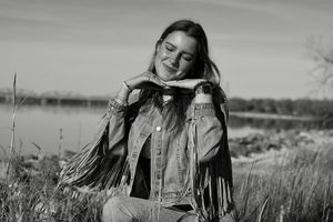 A series of black and white photos showing a person in a field wearing a denim jacket and smiling outdoors.