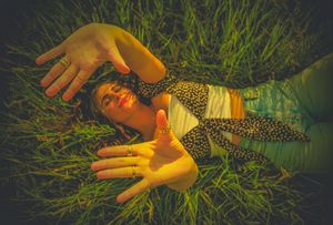 A person lying in tall grass at sunset with dramatic golden lighting and shadows creating a dreamy atmosphere.