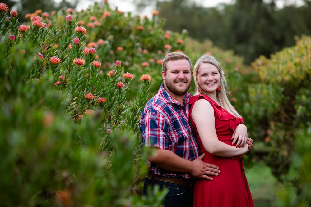 Couple holding each other and smiling at the camera in a scenic outdoor location.