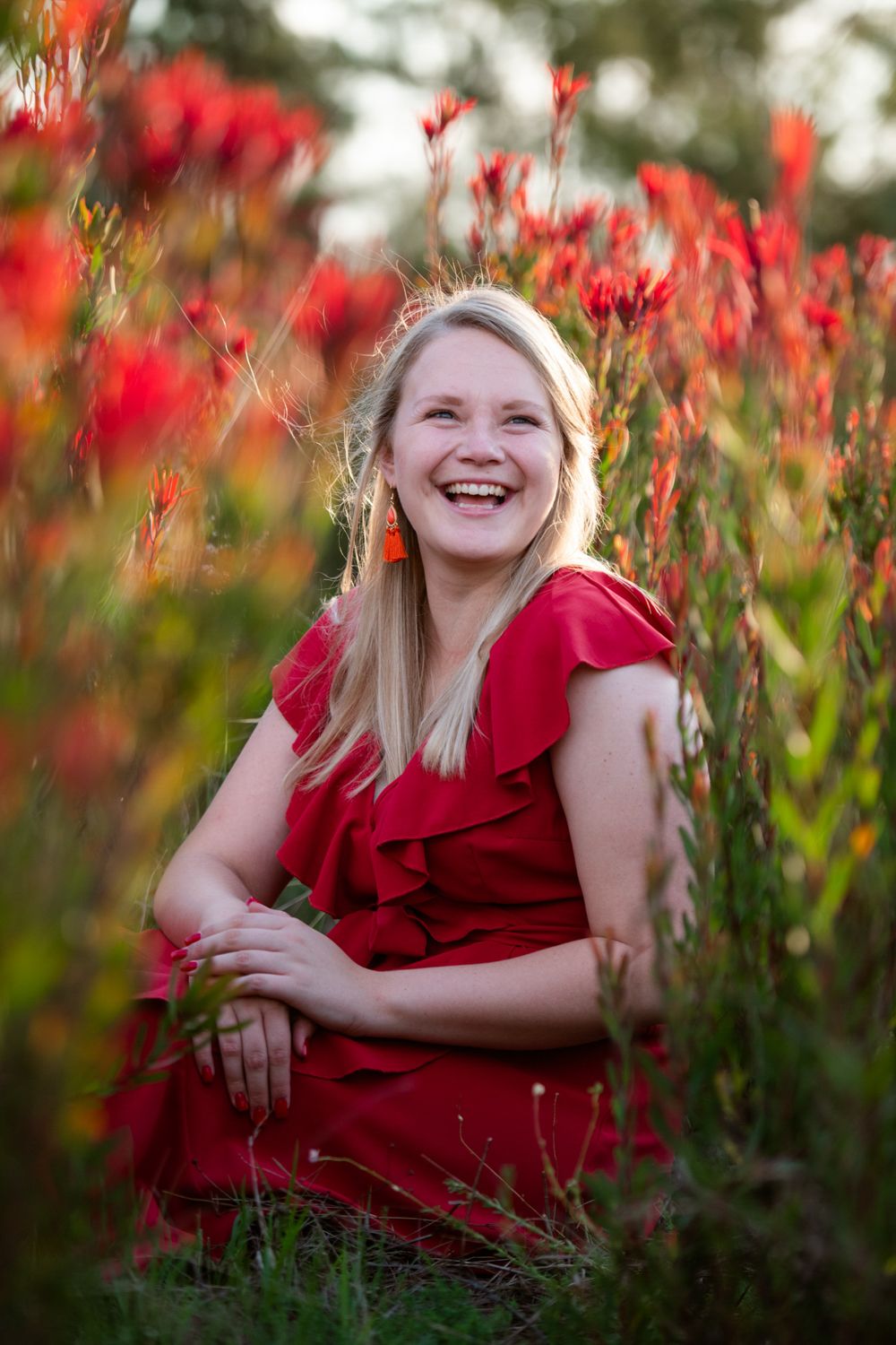 Portrait of Leandri wearing a red dress posing in a Protea field.