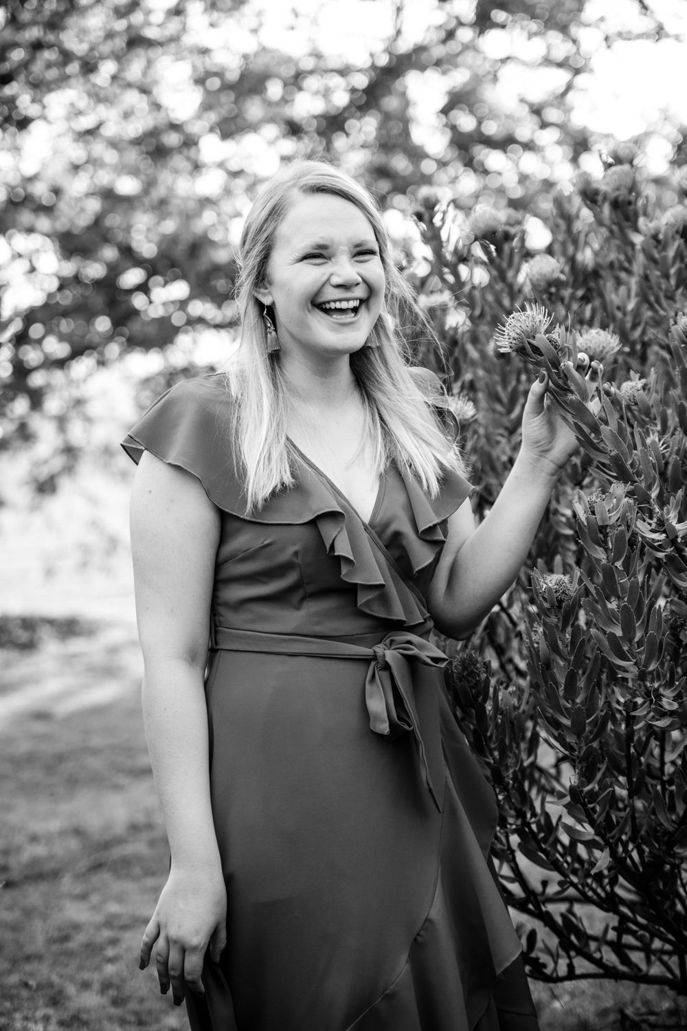 Black and white solo portrait of the bride-to-be laughing candidly in nature.