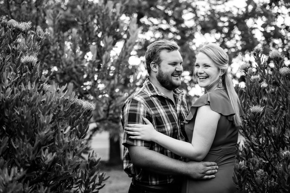 Black and white portrait of a couple standing in a dense Protea garden.