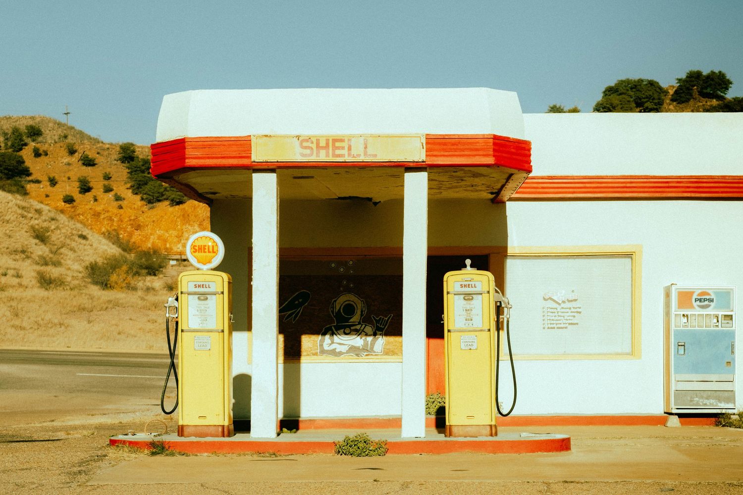 Vintage Shell gas station in desert landscape with retro white and orange color scheme.