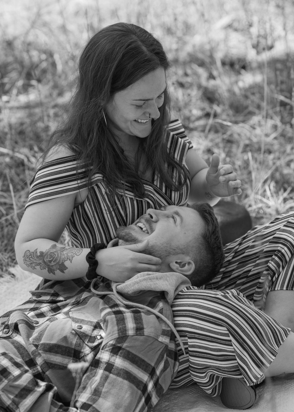 Black and white photo of a laughing couple enjoying a playful outdoor moment together.