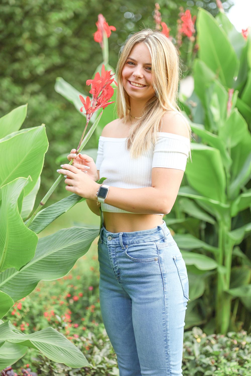 Summer garden portrait with bright red canna lilies and casual attire.
