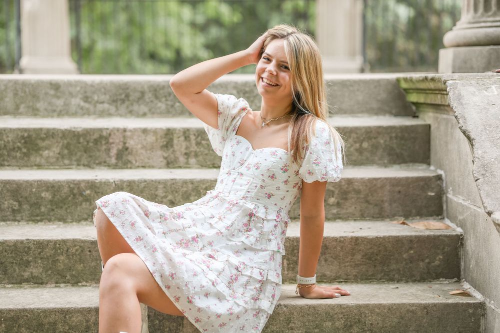 White floral dress worn on stone steps near classical architecture columns.