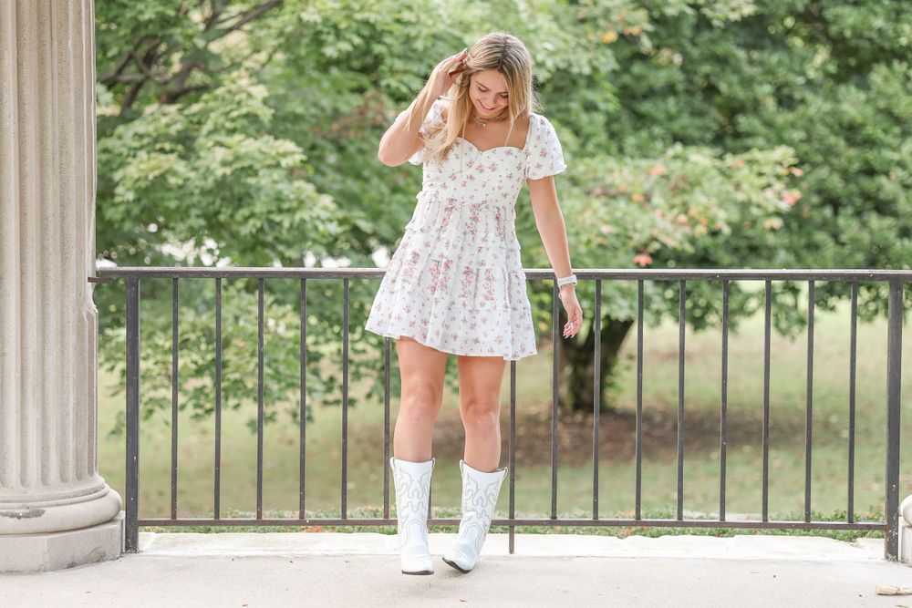 White boots and floral dress ensemble photographed on stone steps with columns.