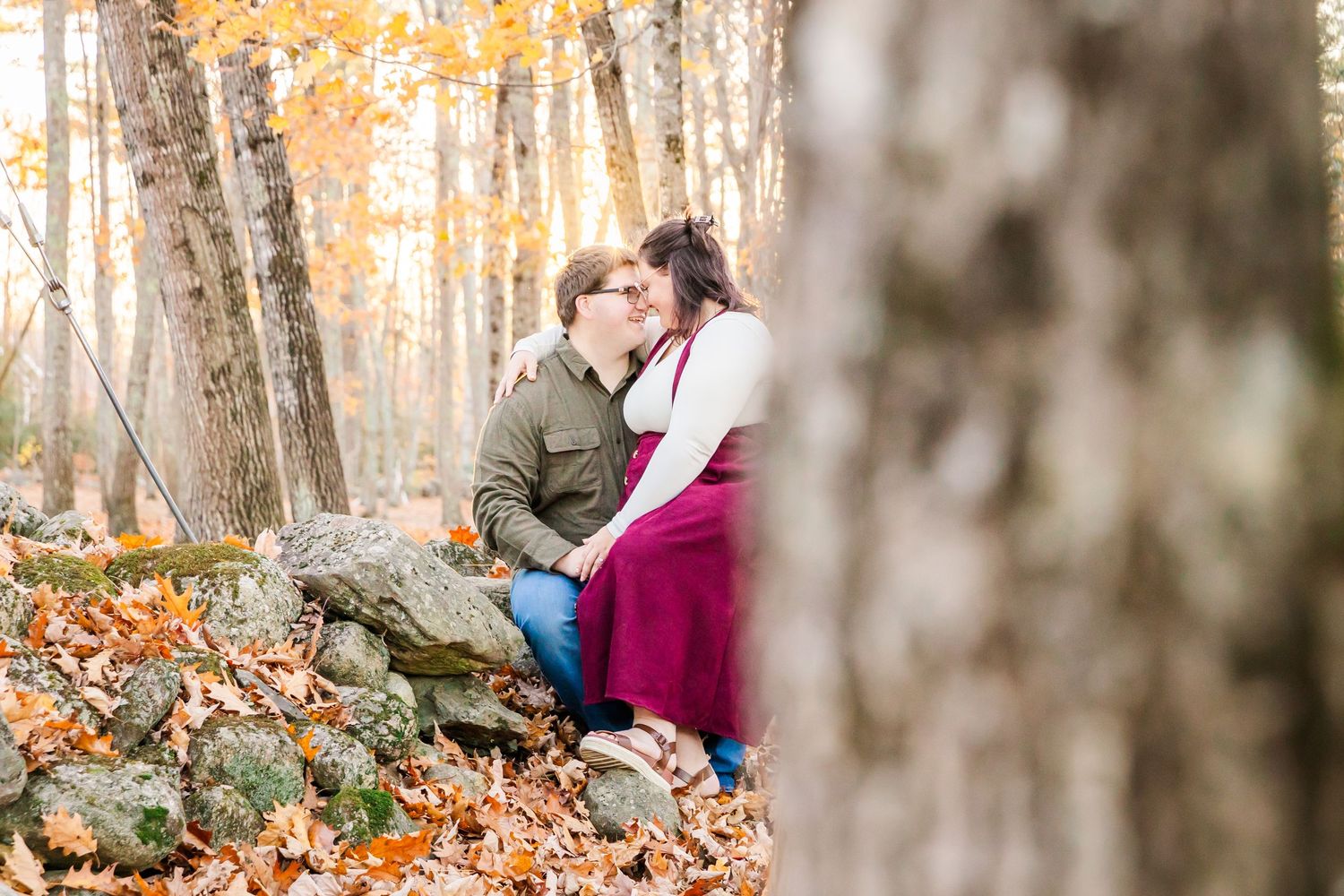 Intimate autumn engagement session on rocks surrounded by fall foliage.