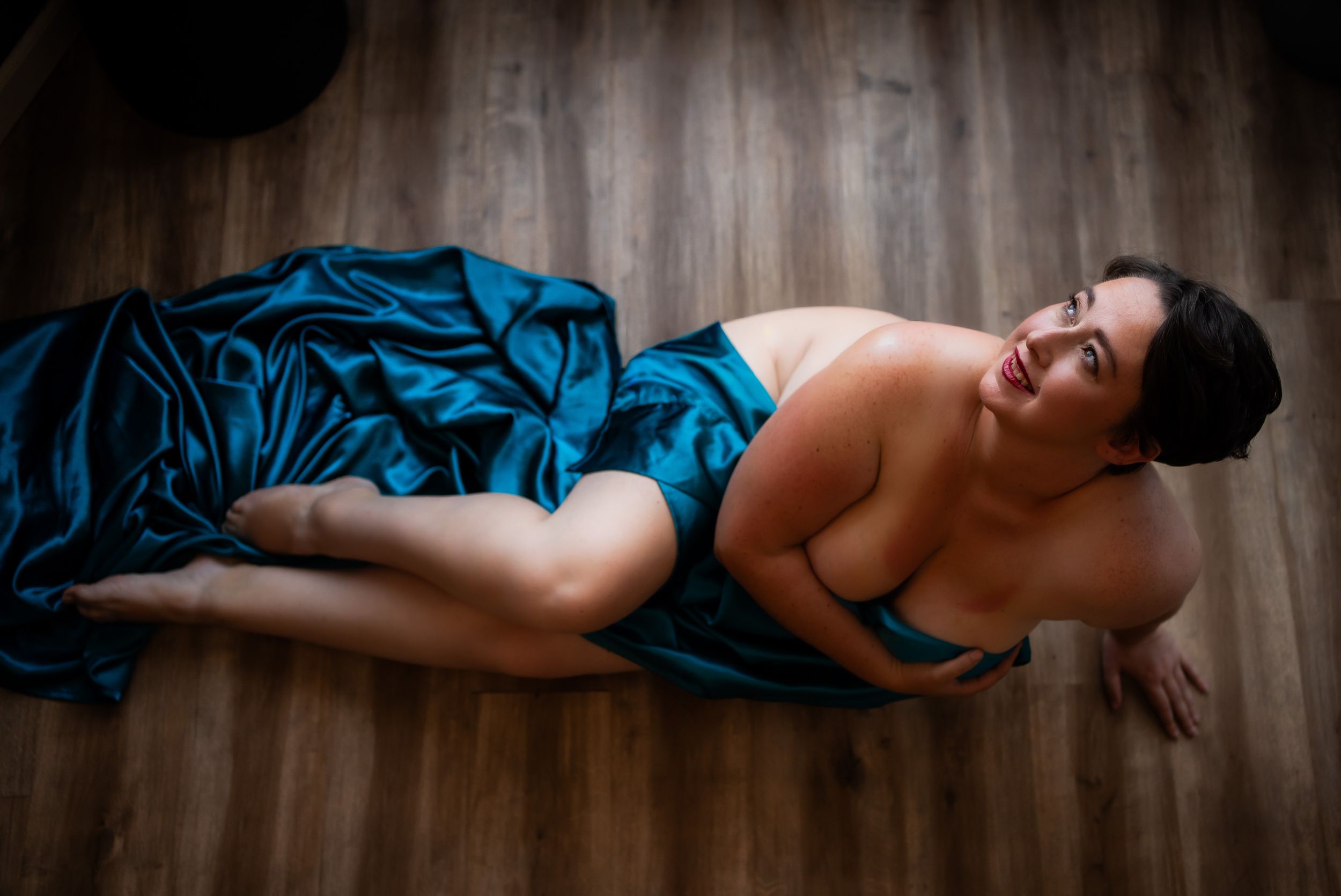 A figure in a blue silk dress lies gracefully posed across multiple artistic boudoir photographs.