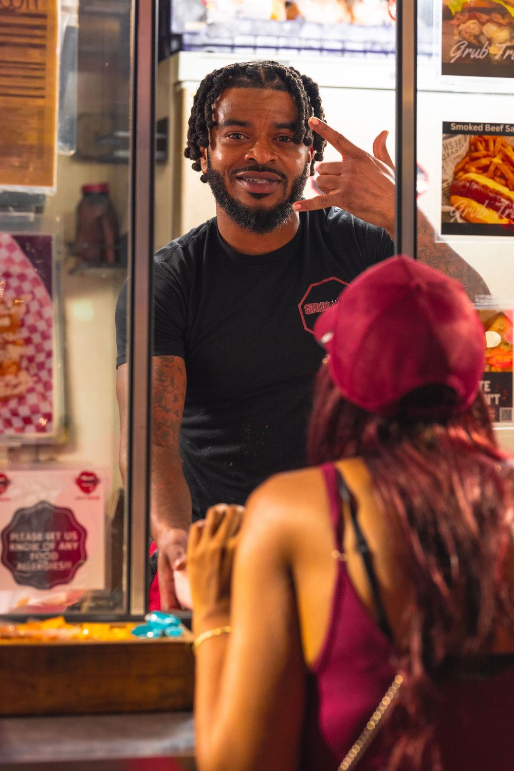 Food service worker with dreadlocks smiling while interacting with customer through service window. | Shot By Lo™