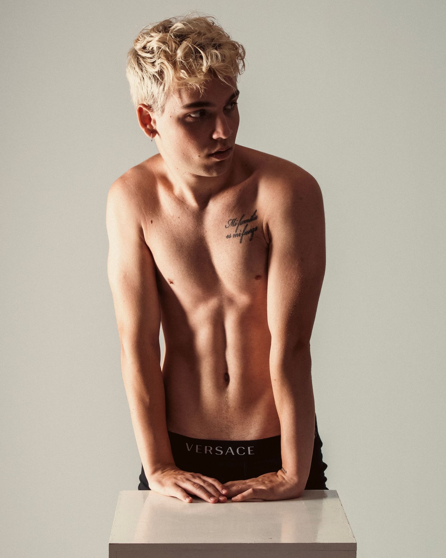 Fashion photo of a model posing shirtless against light background wearing designer underwear.