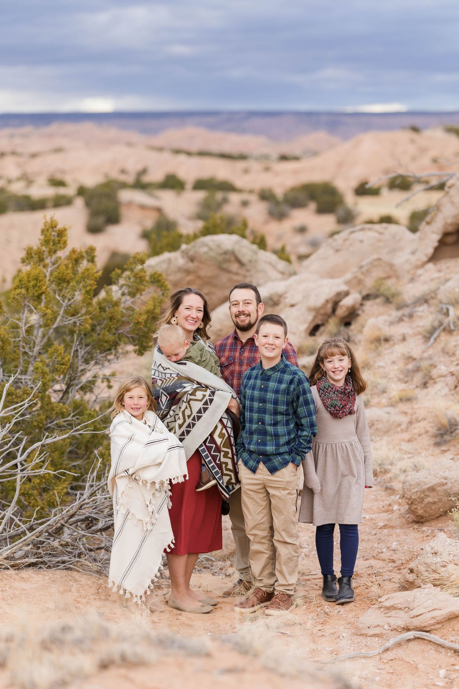 Family group photo on rocky terrain with desert landscape in background.