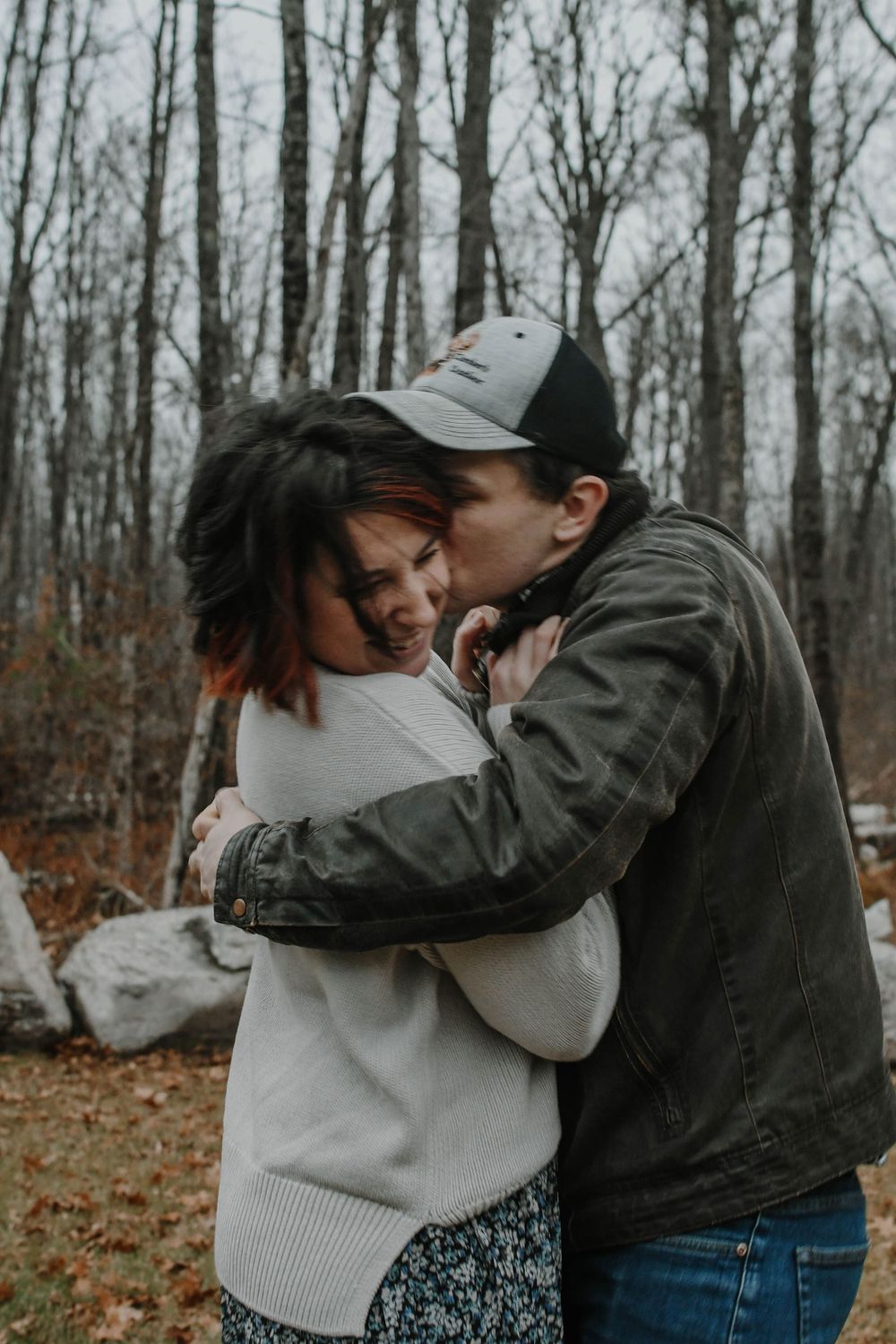 Intimate embrace captured in moody forest setting during fall season.