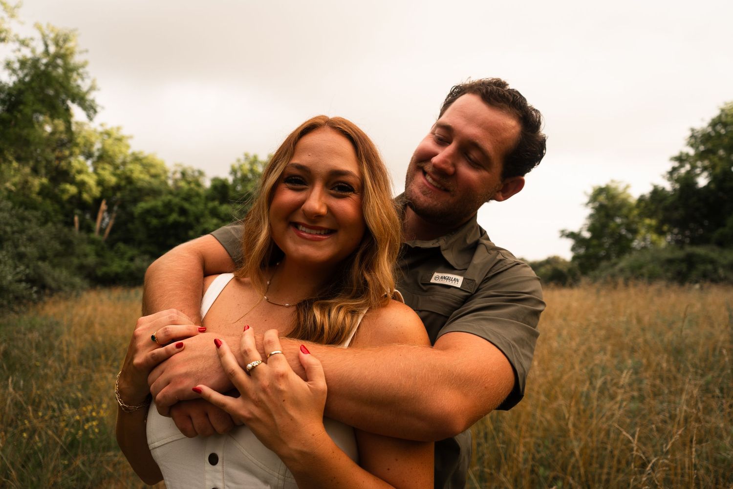 A couple shares joyful embraces and laughter in a series of candid outdoor photos in a golden field at sunset.