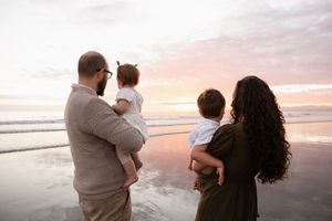 family looking towards the beach, parents holding the kids