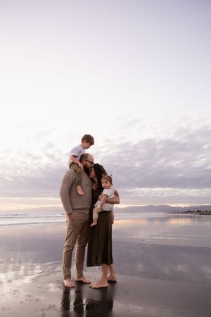 Family cuddling in together during sunrise session at the beach christchurch