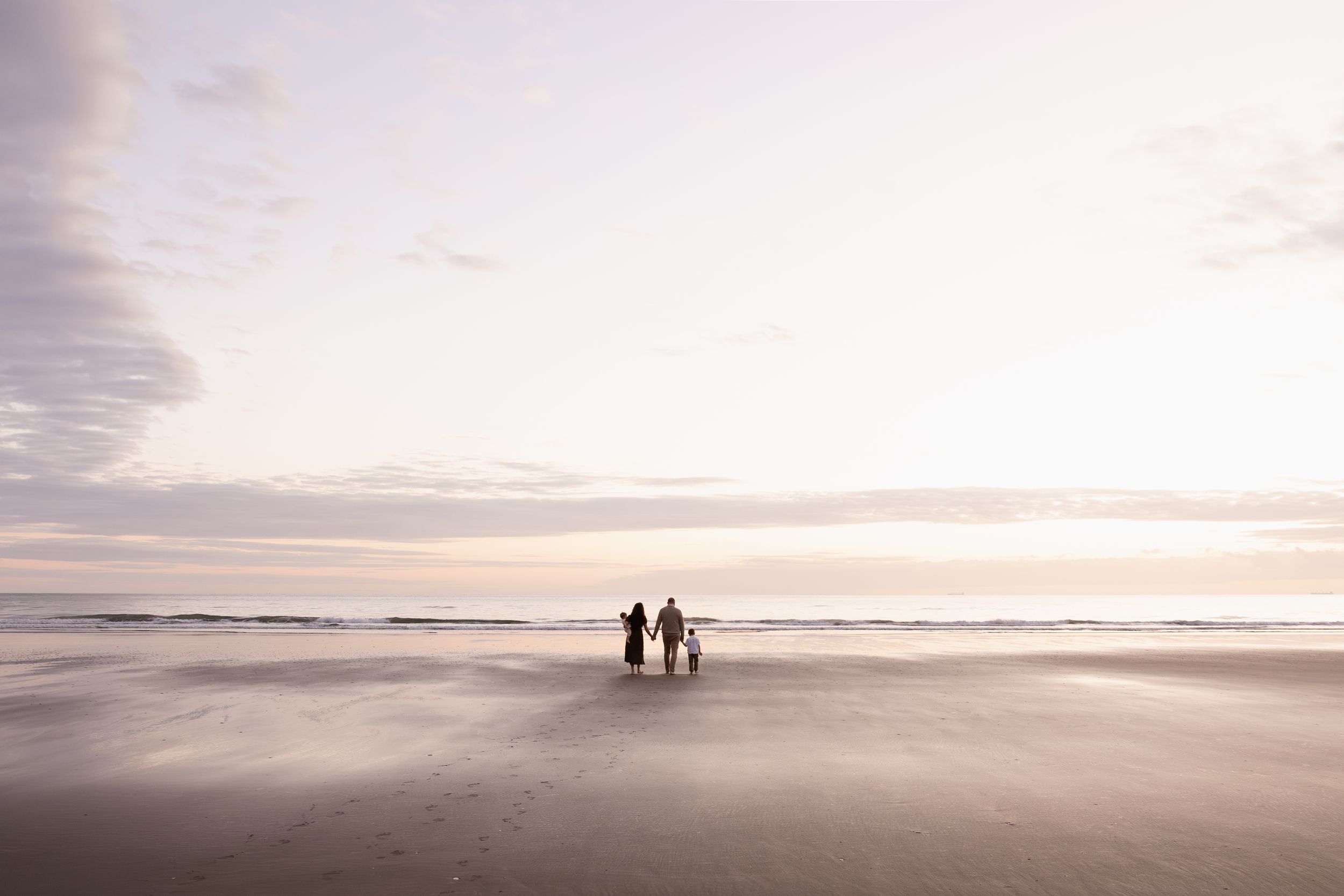 wide angle image of family walking towards the beach during sunrise session, Christchurch