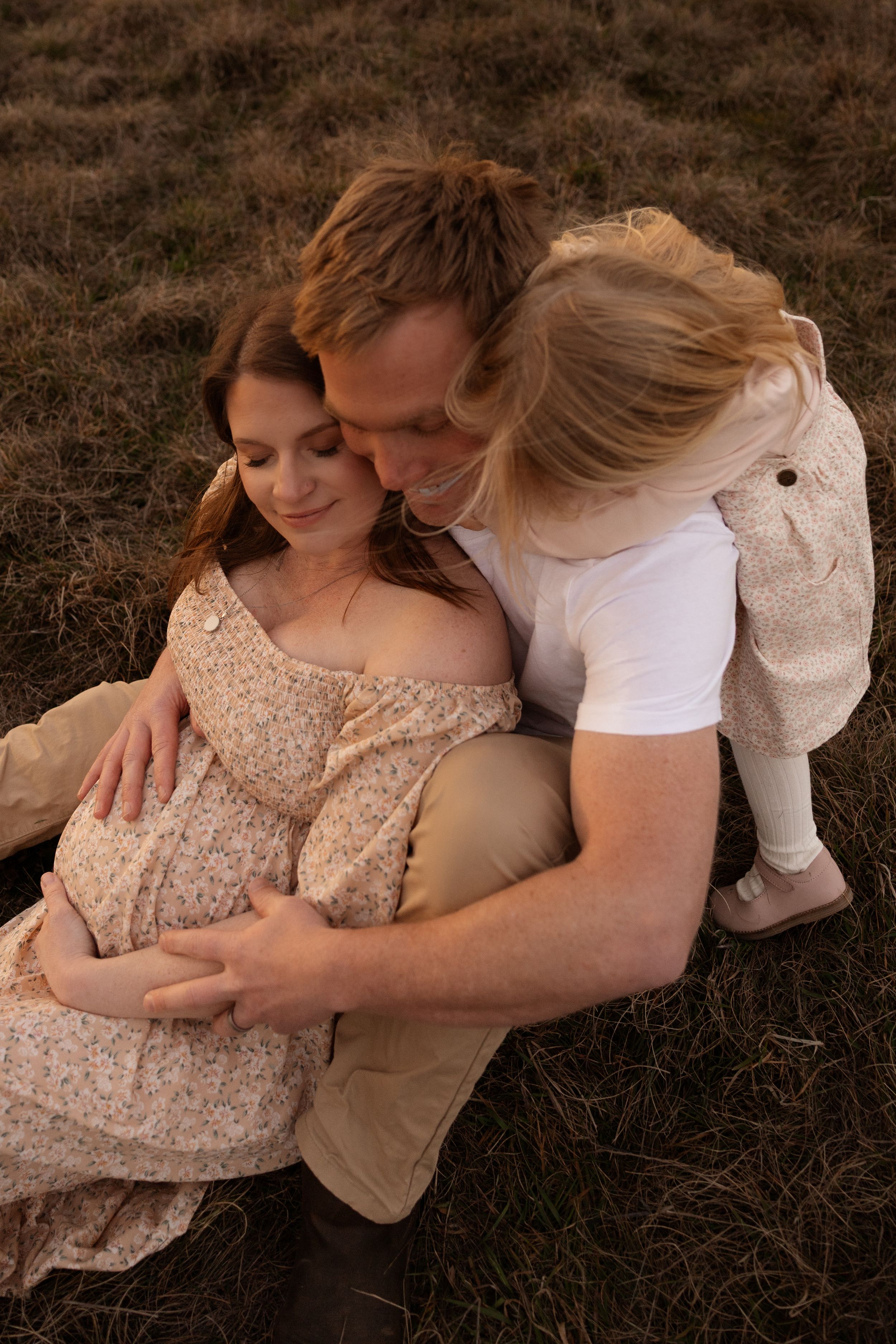 mum and dad lying down cuddling daughter during maternity session