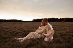 mum and dad lying down cuddling daughter during maternity session
