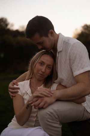 Couple sitting on bench during couples session at The Groynes during sunset