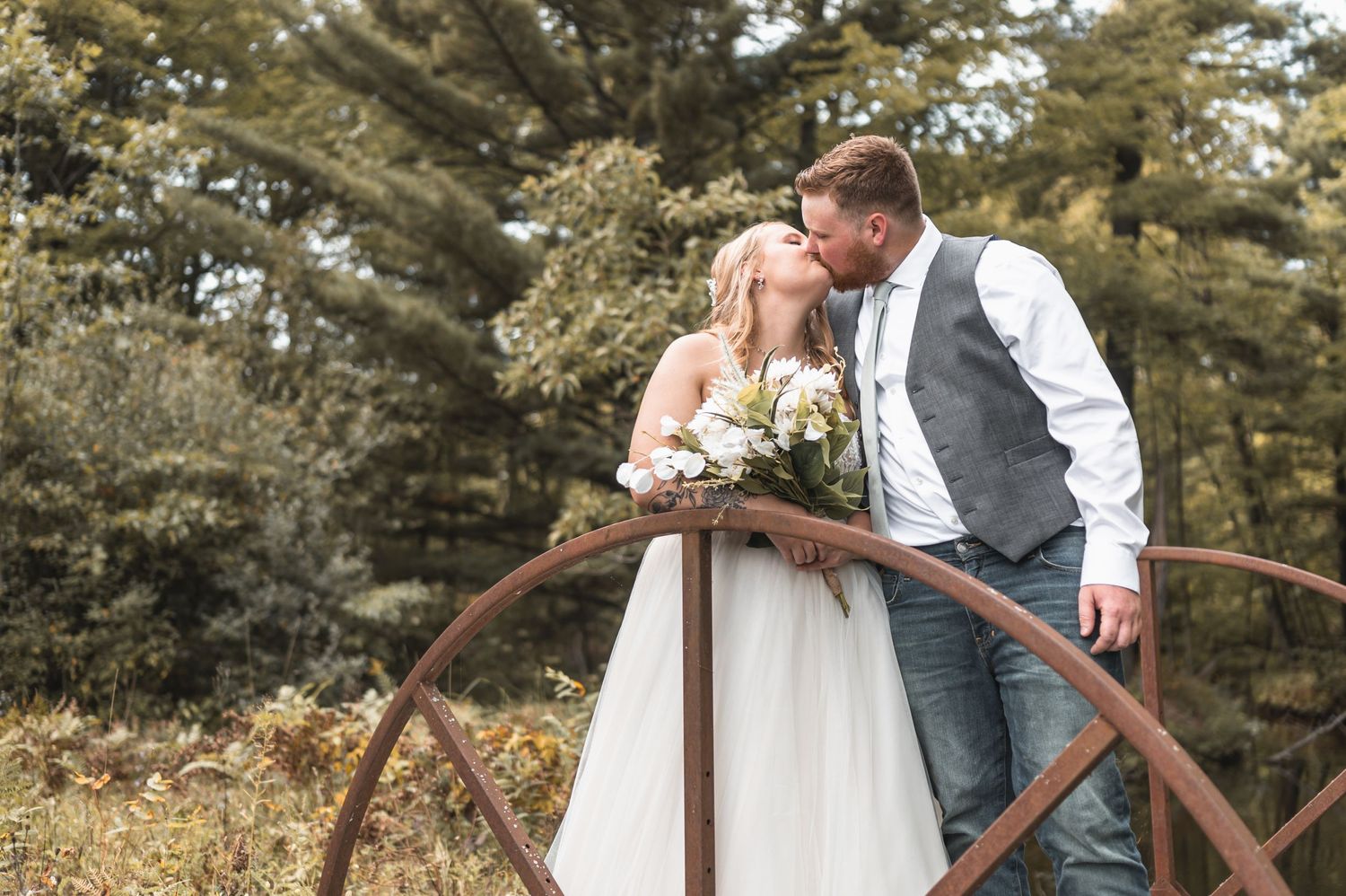 A romantic wedding photo with a couple sharing a moment by a vintage wagon wheel.