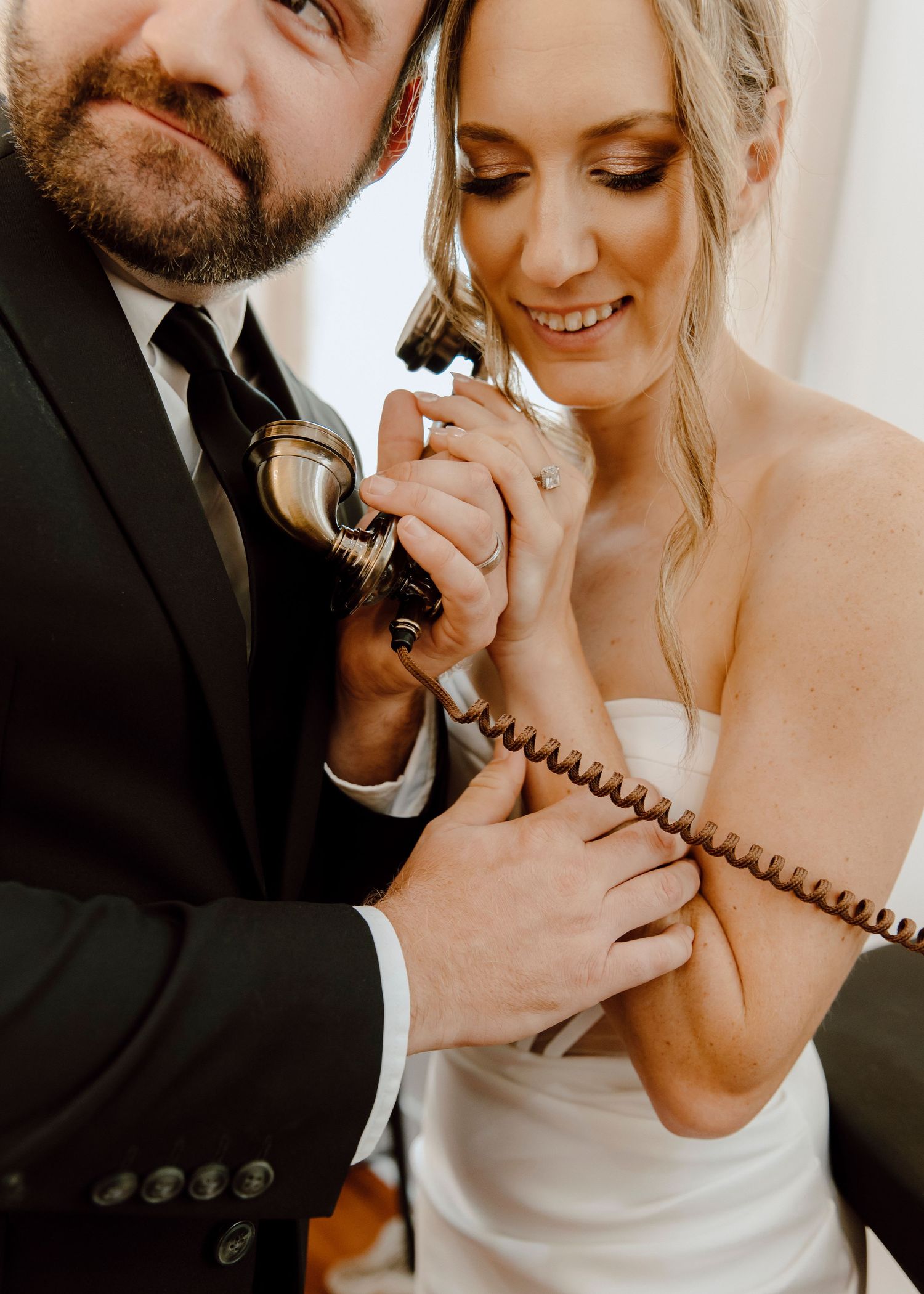 Couple playfully sharing a vintage telephone during wedding photoshoot. New Orleans