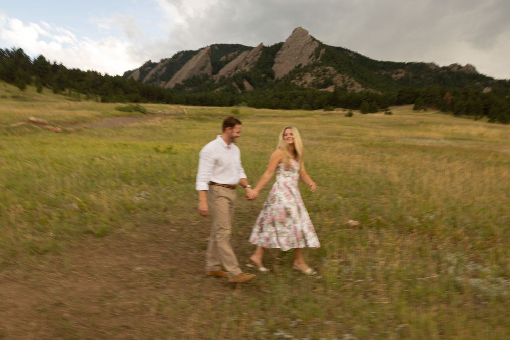 A couple dances together in a meadow with the Flatirons mountains of Colorado creating a dramatic backdrop.