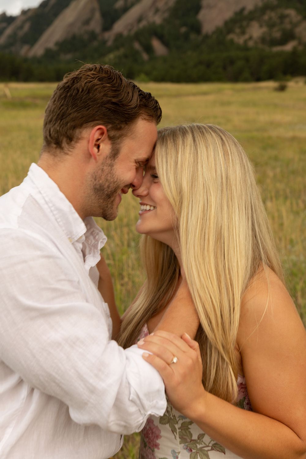 A romantic moment captured in front of the majestic Flatirons mountains during golden hour.