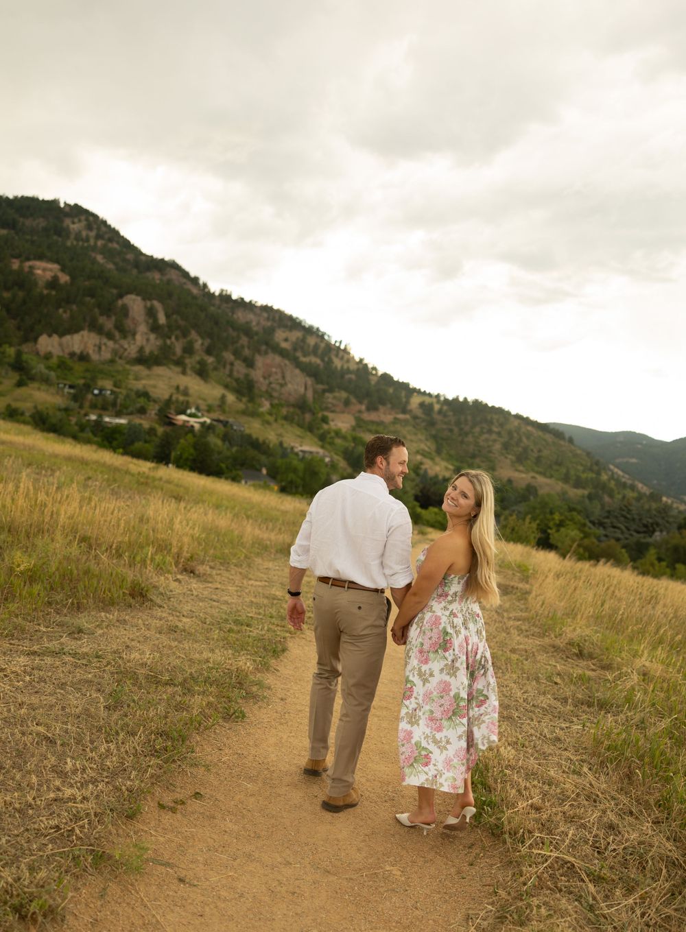 A couple walks hand in hand along a mountain trail during sunset in Boulder, Colorado.