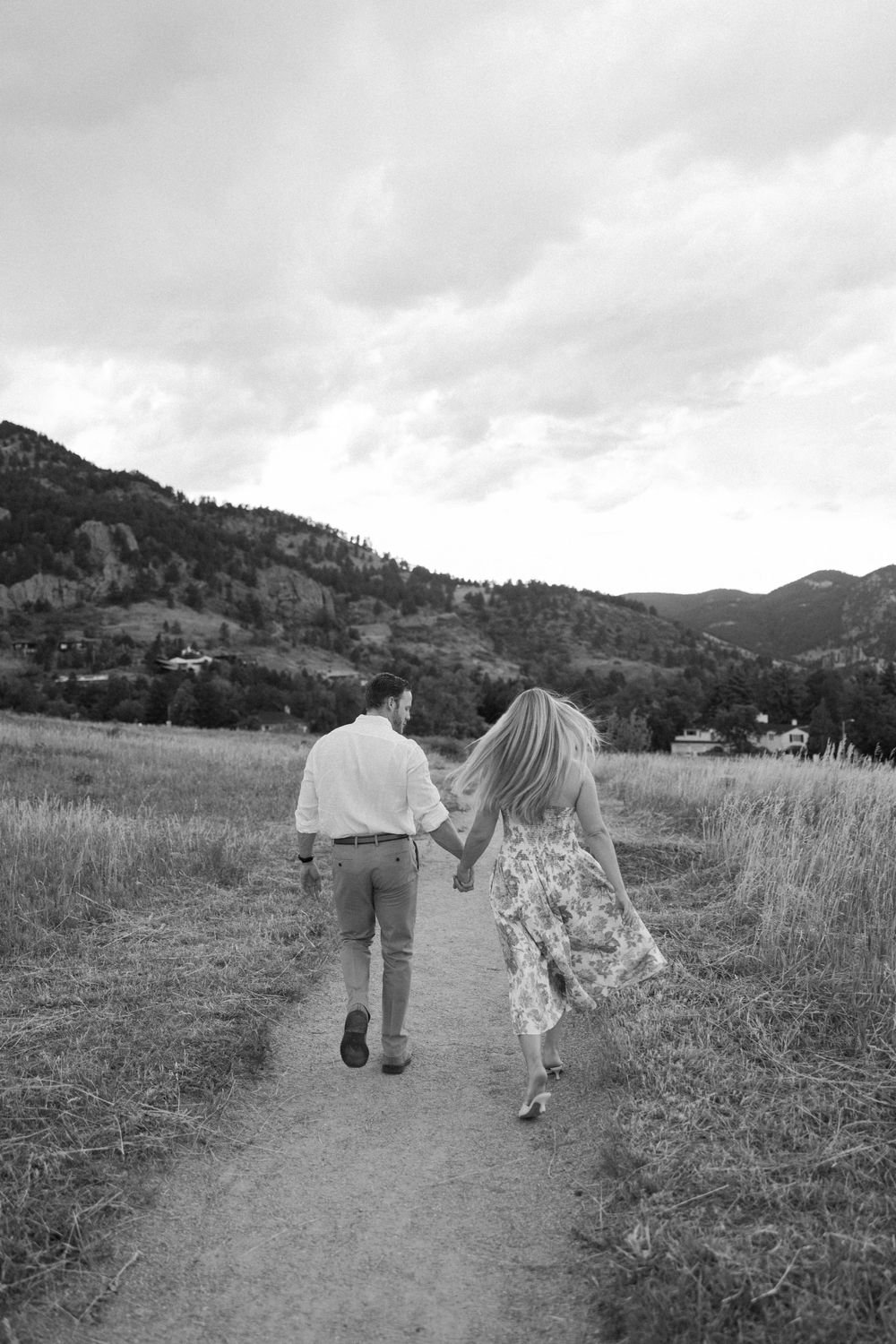 Black and white photo of a couple walking along a mountain path in Colorado.