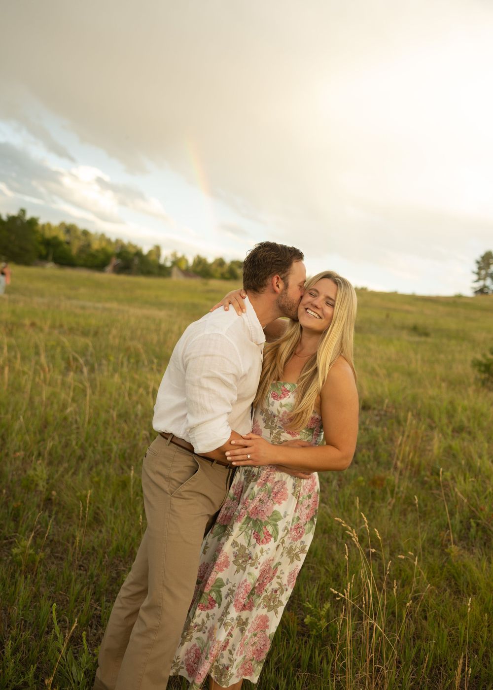 Couple shares intimate moment in mountain meadow during golden hour.