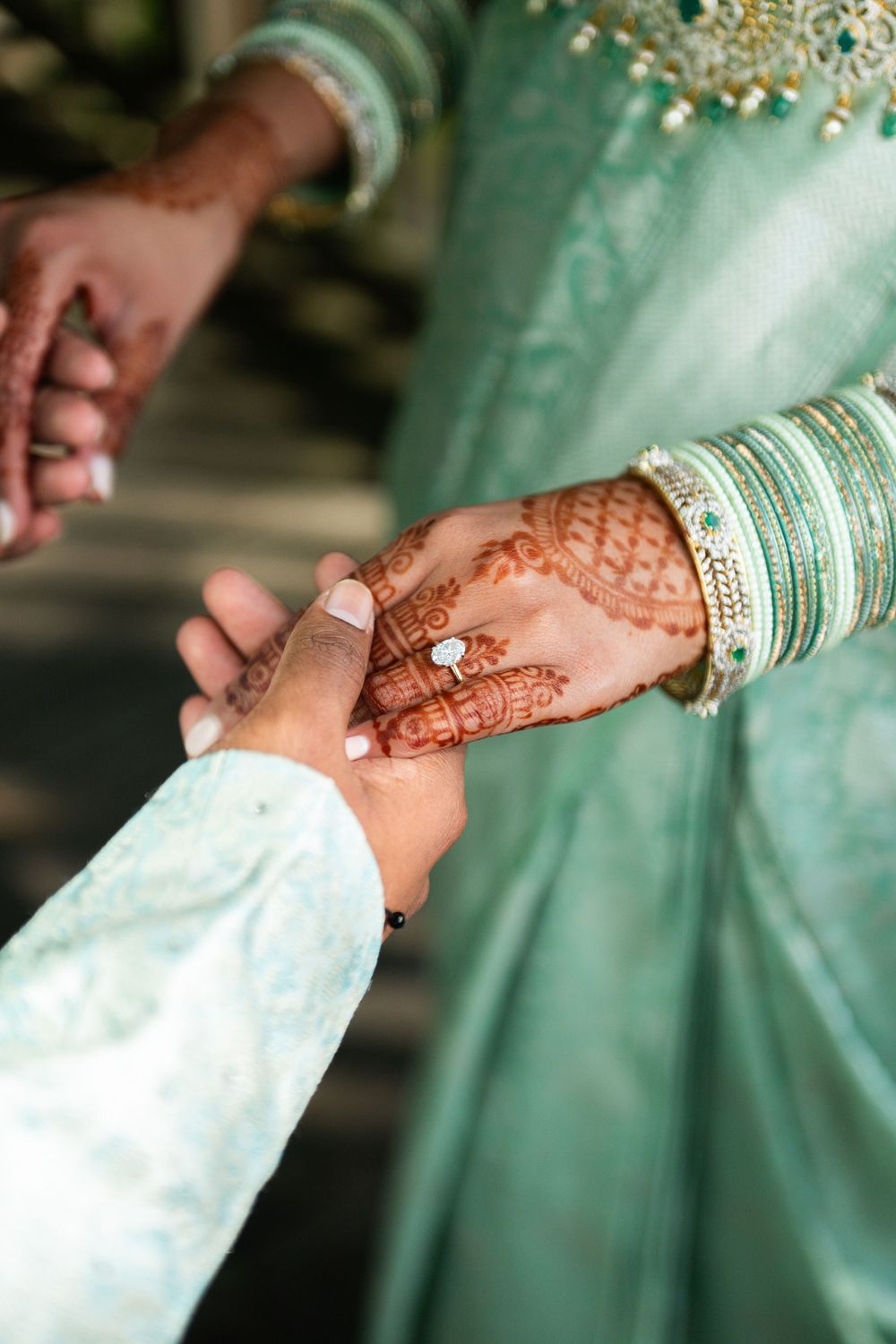 Beautiful capture of traditional henna adorned hands with bangles during an Indian wedding ceremony against turquoise background.
