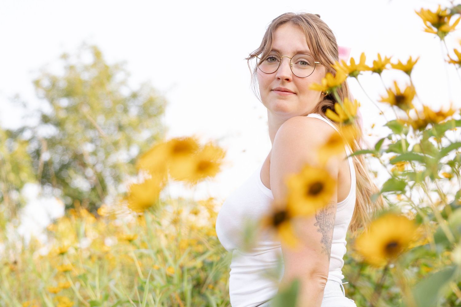 A soft portrait among blooming yellow sunflowers with dreamy bokeh effect.