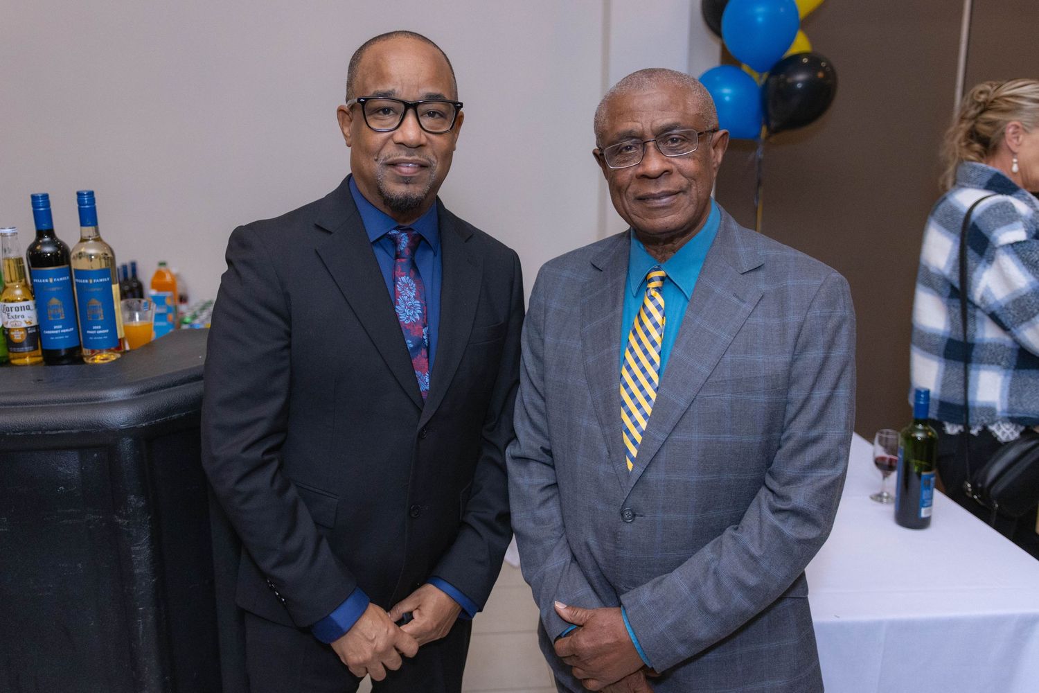 Two professionals in suits posing at a formal event.