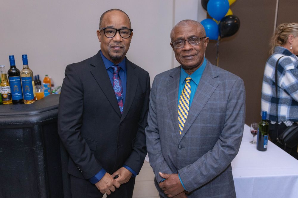 Two professionals in suits posing at a formal event.