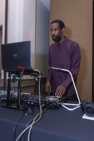 DJ performs at an event using professional equipment and a Dell laptop.