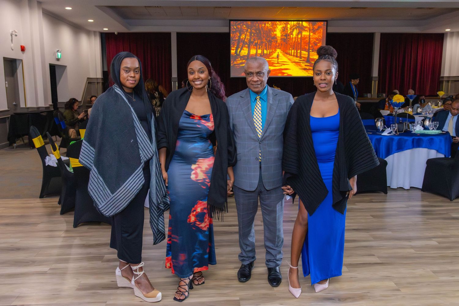 Group of four people in formal attire pose at evening event.