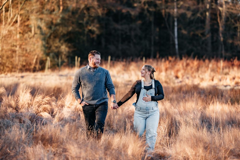 babybauchshooting winterliches wetter ein paar am Waldrand an einem Feld mit Gräsern
