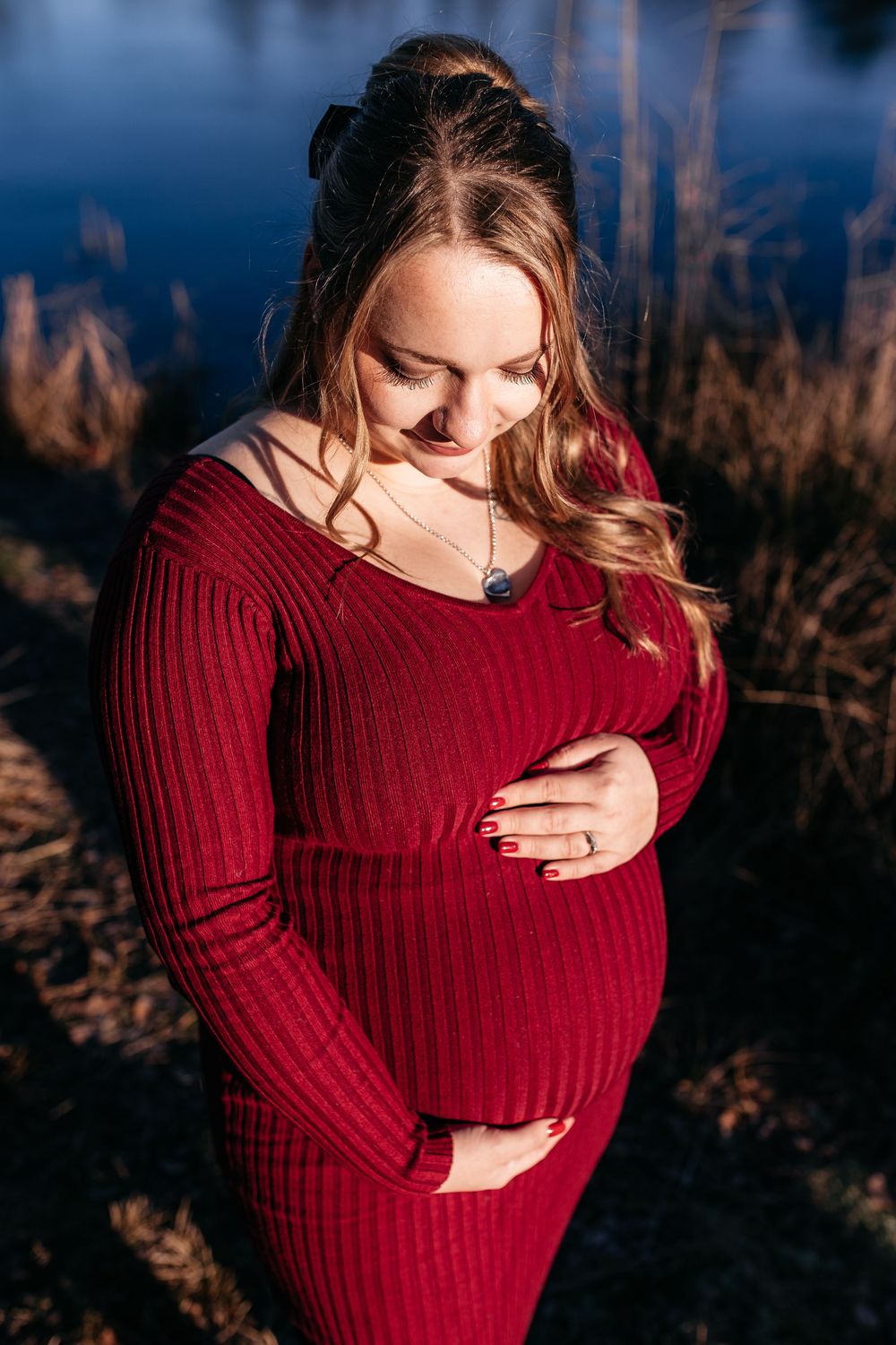 babybauchshooting winterliches wetter die werdende mama am Waldrand vor einem See