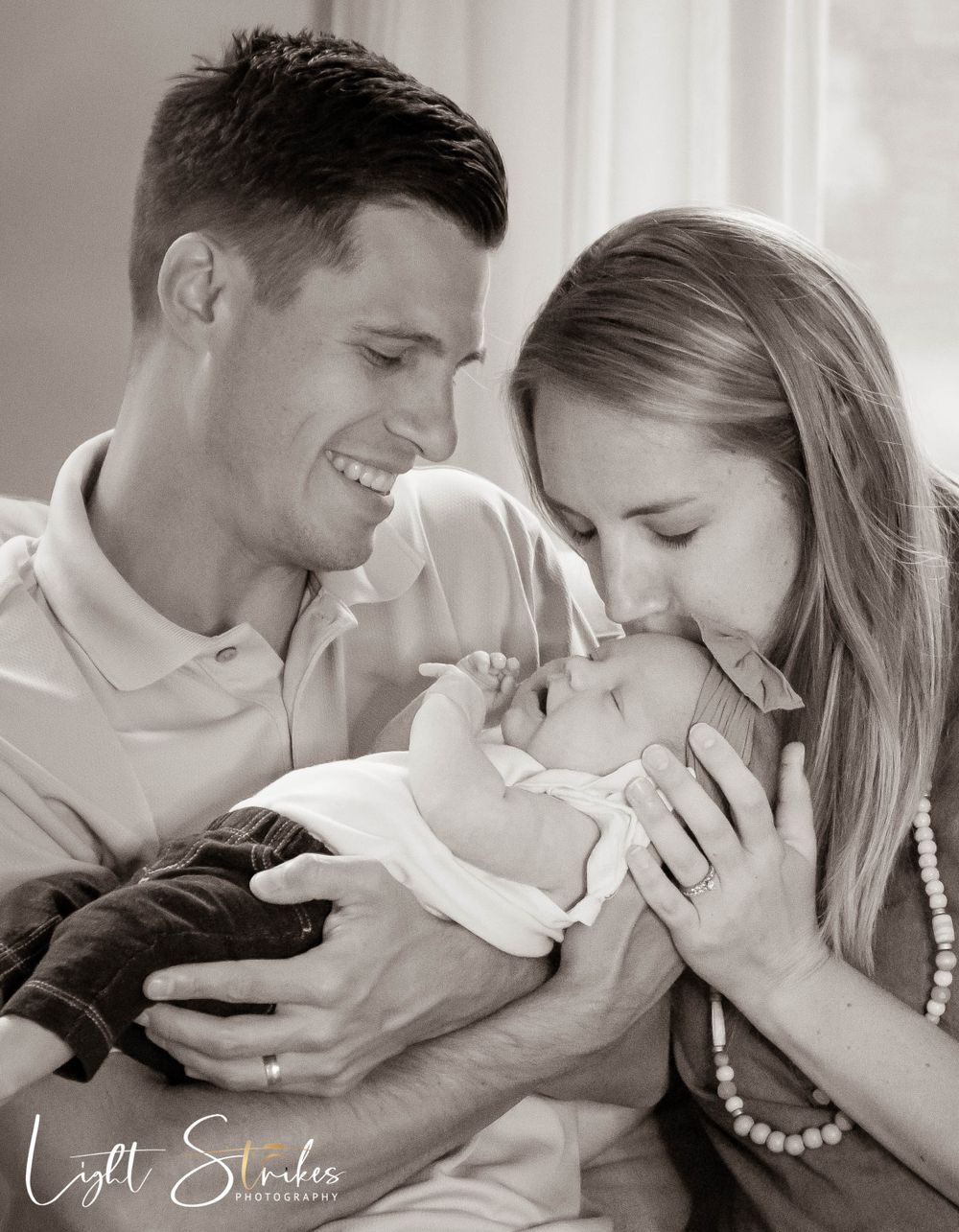 Family photographer captured a heartwarming family moment as parents and child share joyful laughter on a couch together.