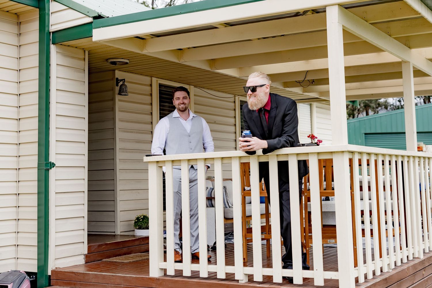 Two people having a conversation on a white porch with railings.