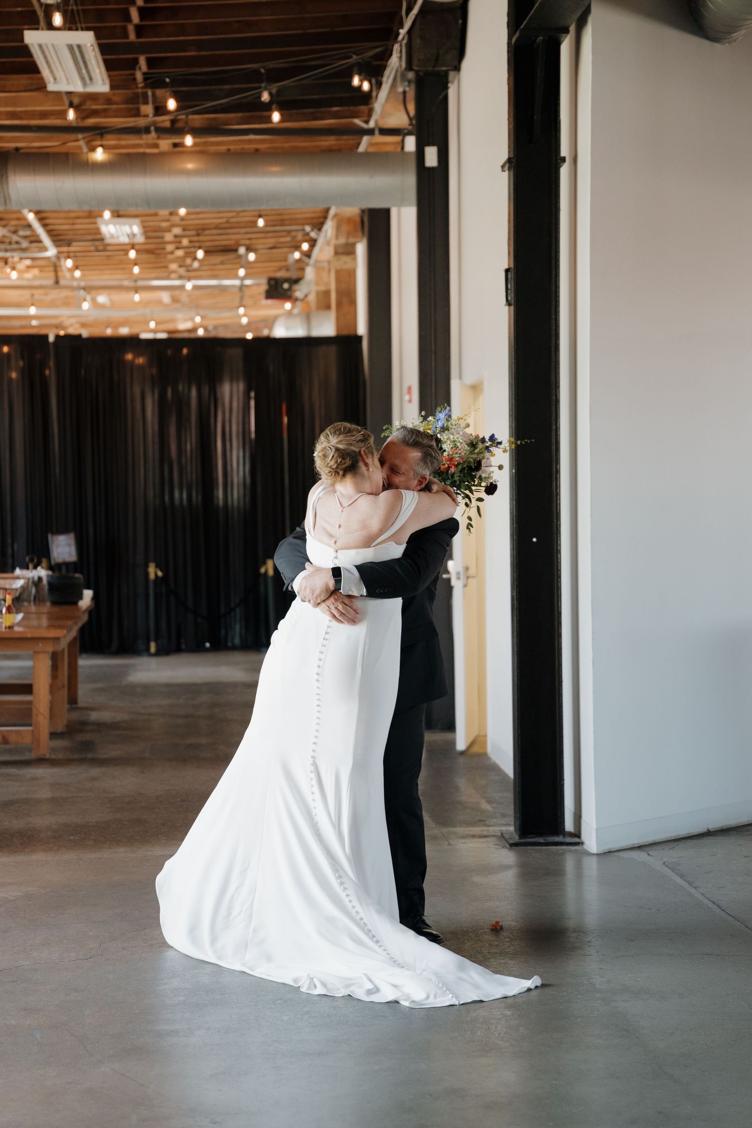 A romantic first dance sequence showing a couple spinning in an industrial-style venue with string lights and concrete floors.