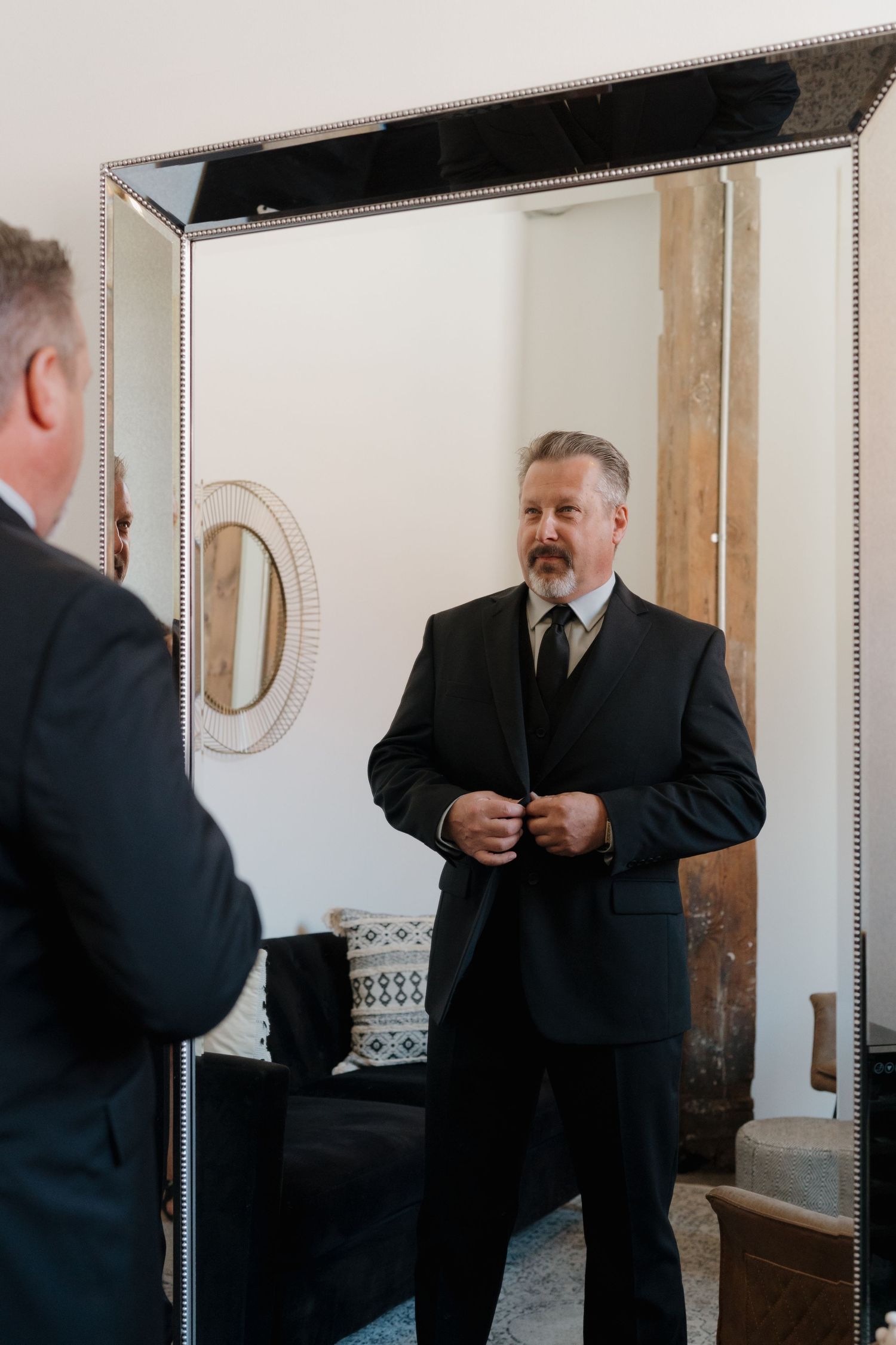 A sequence showing a man in a black suit adjusting his tie and getting ready in front of a mirror.