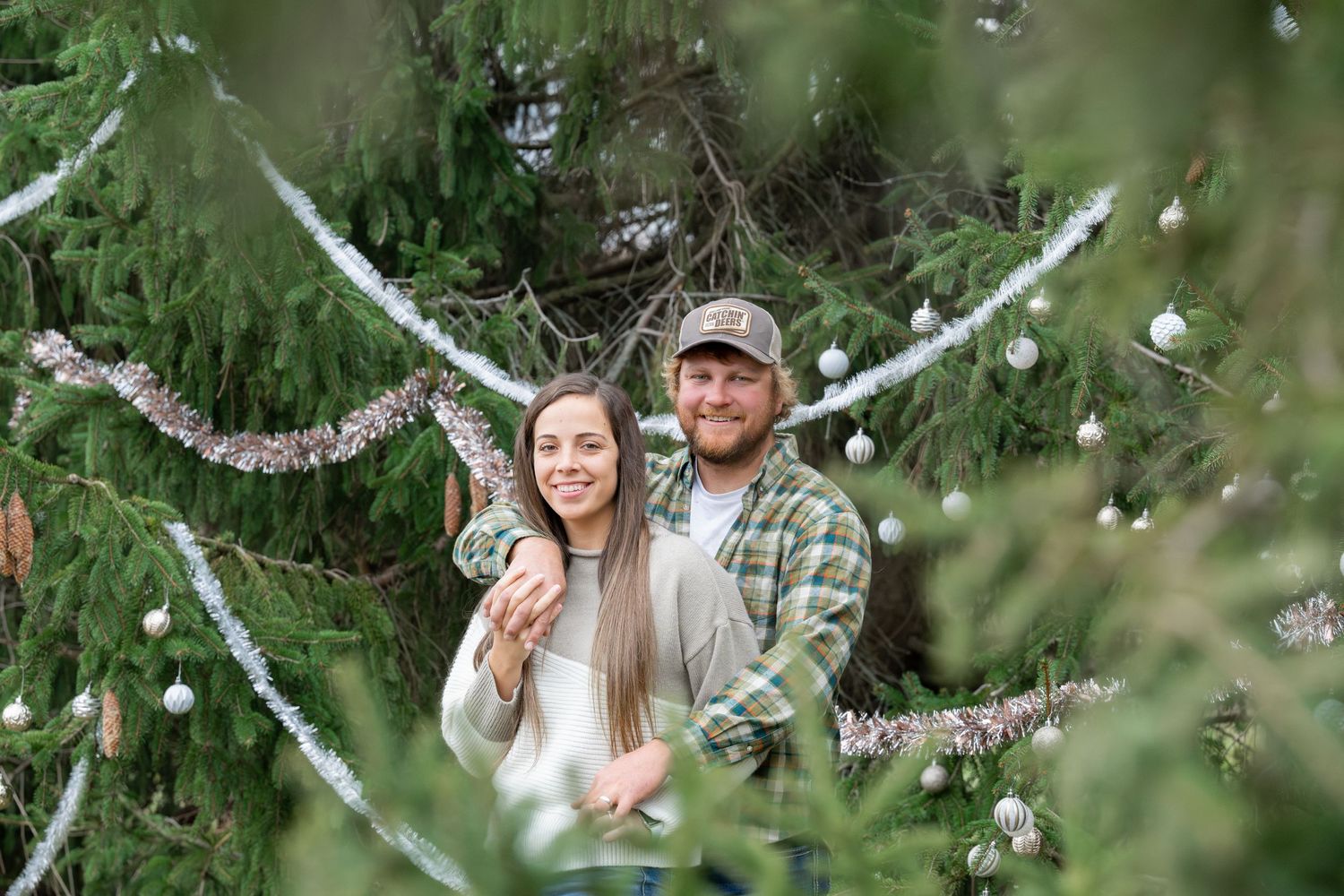 Festive winter portrait in front of an evergreen tree decorated with twinkling lights and garland.