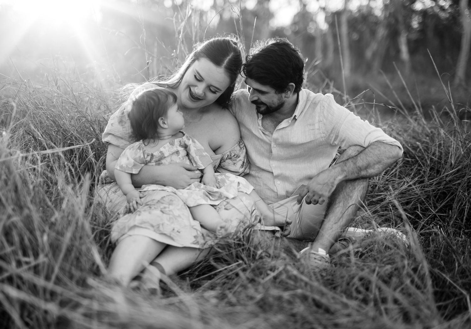 Maternity photography in golden field during sunset with dramatic sky.