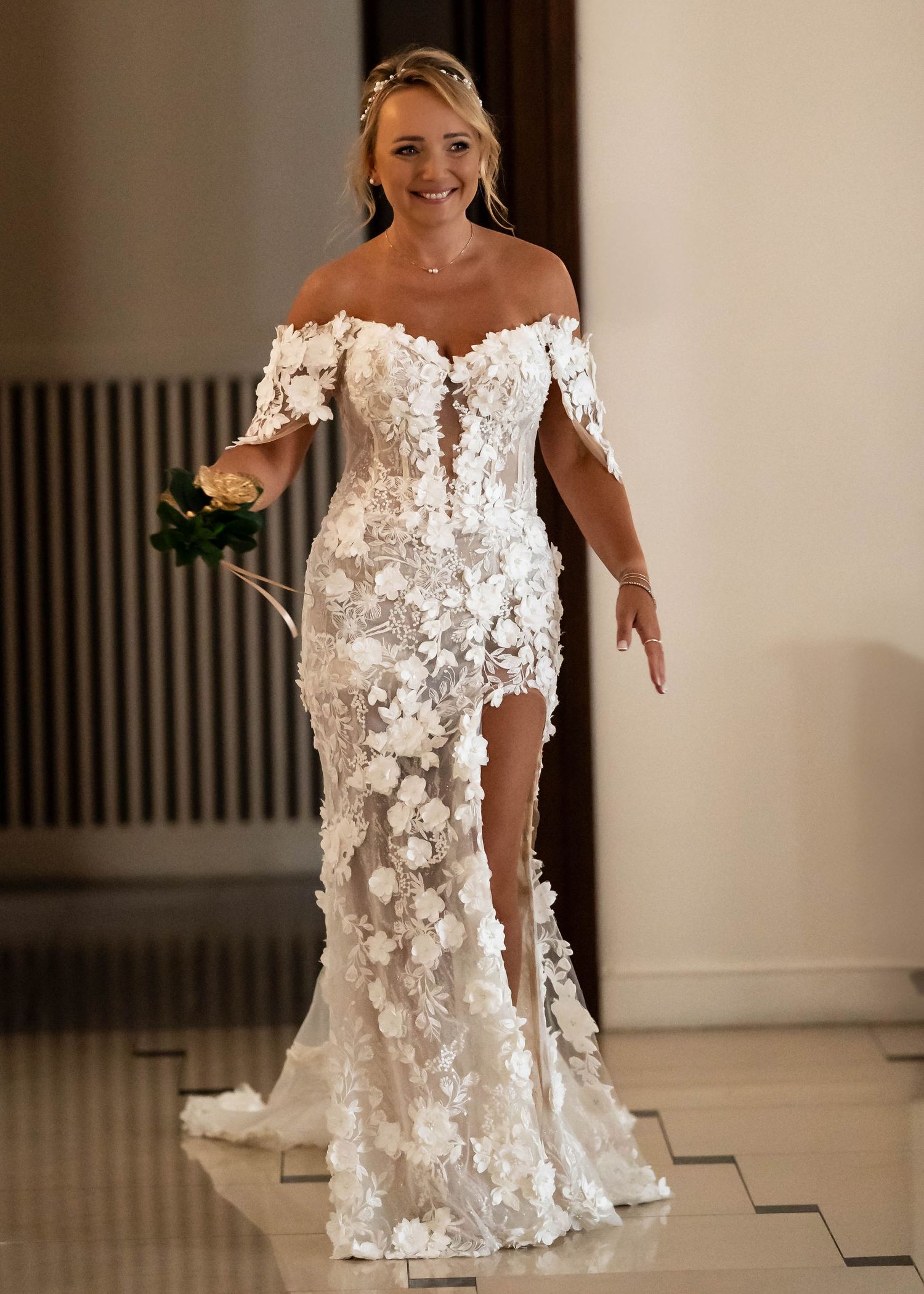 An off-shoulder wedding gown with intricate floral appliques and a sophisticated side slit.