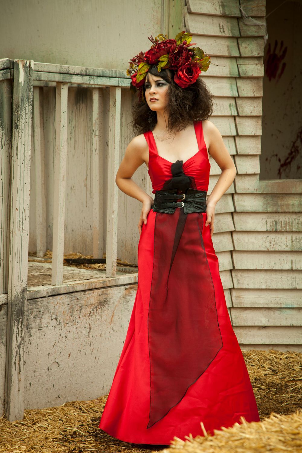 Dramatic red gown with black corset detail poses near rustic porch steps.